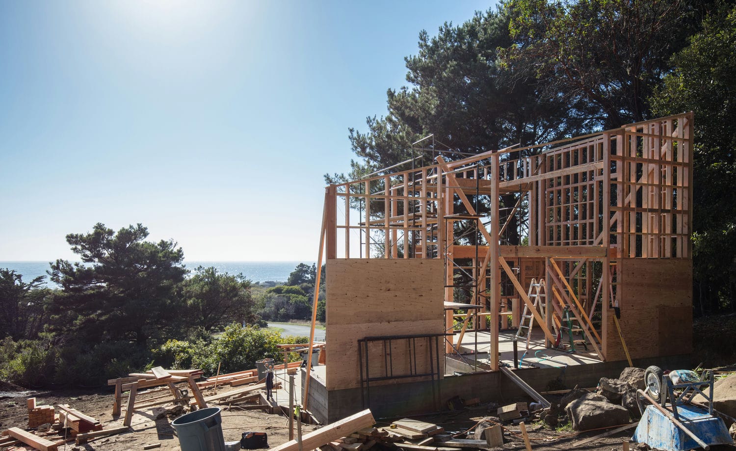 Custom home mid-build with partially framed walls and sheathing representing the residential framing process from sill plate to roof