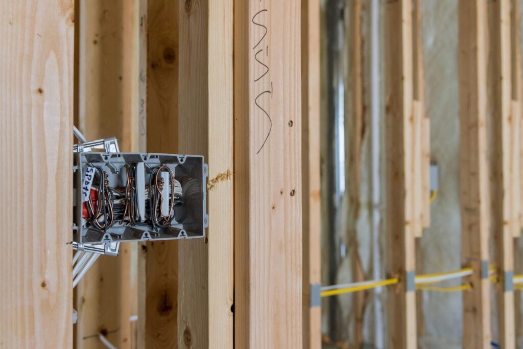 Electrical rough-in wiring and junction box installed in a wall cavity during framing inspection readiness