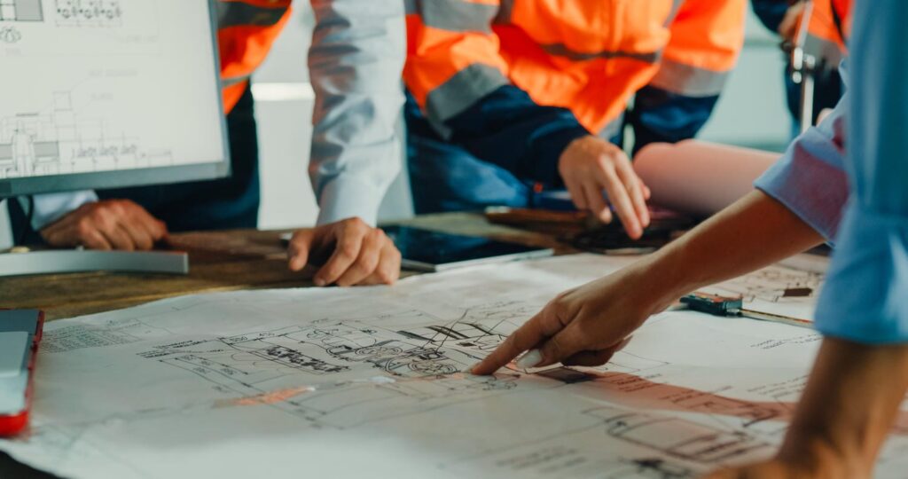 Framing and engineering team reviewing structural drawings together on a custom home project, pointing to details during a coordination meeting