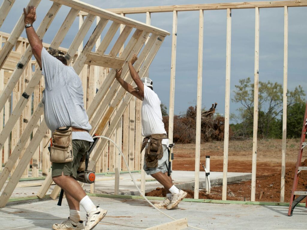 Framing crew lifting and standing an exterior wall section during custom home framing