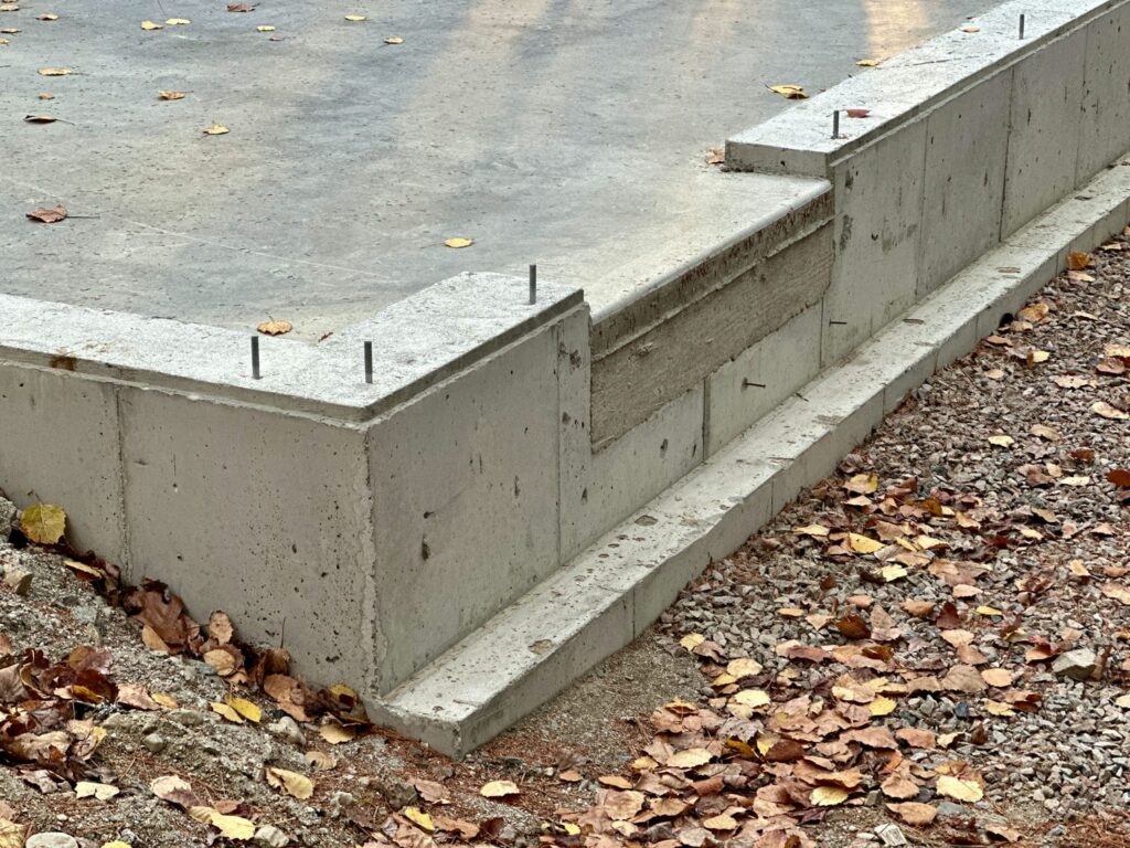 Completed concrete foundation with anchor bolts and stepped wall section ready for sill plate installation and custom home framing