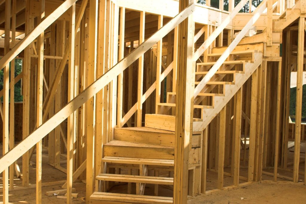 Roughed-in staircase with wood stringers, OSB treads, and surrounding wall framing visible during a custom home framing inspection