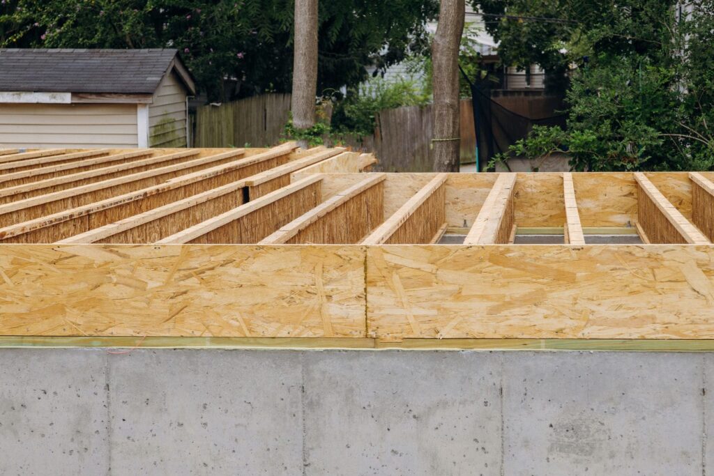 Sill plate on concrete foundation with engineered I-joist floor system installed during custom home framing