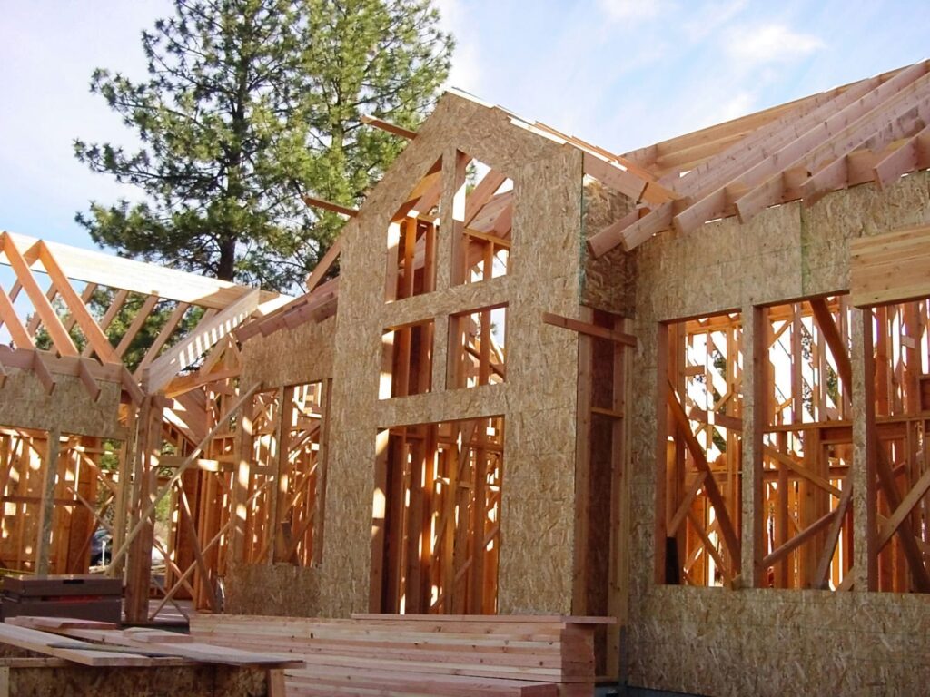 OSB wall sheathing being installed on a custom home frame during the envelope preparation stage