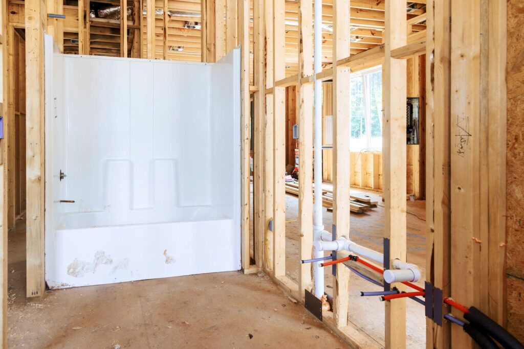 Plumbing water lines and drain stack routed through wood framing, part of coordinating MEP and trades before rough-ins