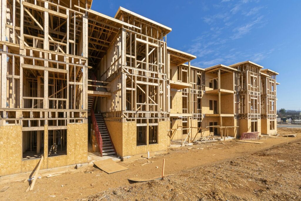 Multi-storey wood-frame multifamily building under construction showing stacked floors and framing considerations