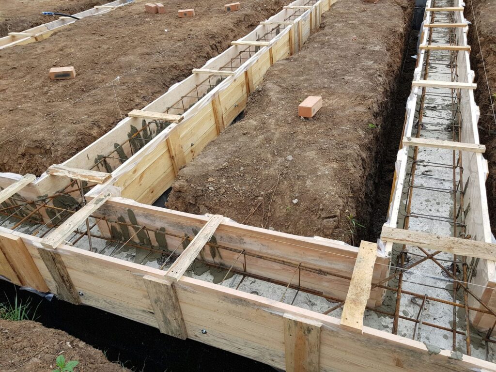 Custom home footing forms with rebar reinforcement tied inside ready for inspection before the concrete pour