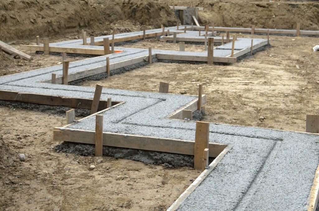 Custom home concrete footings after the pour still within their formwork before the reset for wall forms