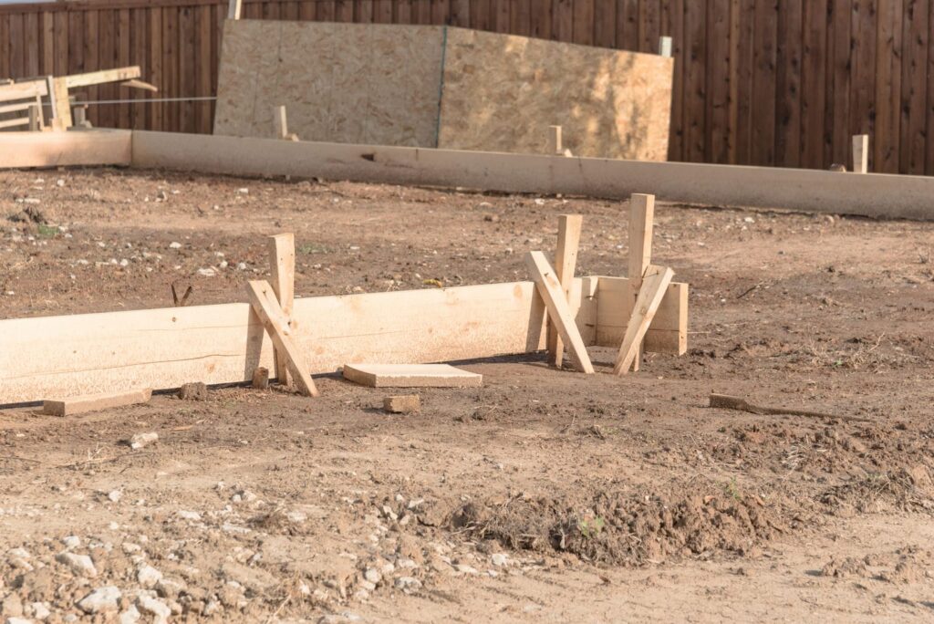 Wooden batter boards and stakes set up during the excavation-ready layout stage of a custom home foundation