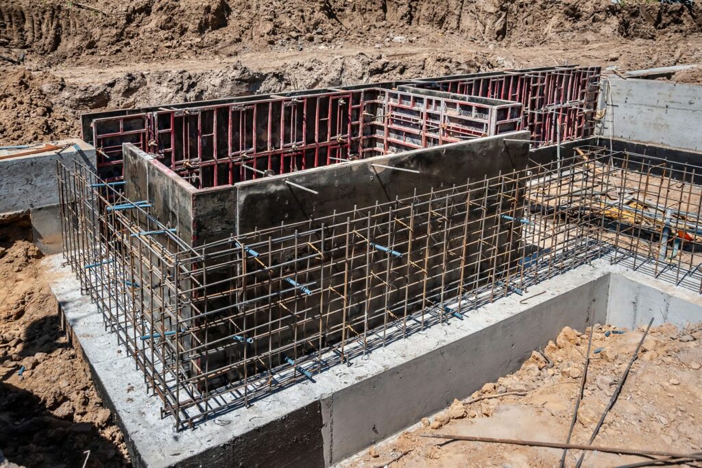 Custom home foundation wall forms with rebar and partially poured concrete walls during